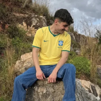Adepto sentado numa rocha com camisola amarela
